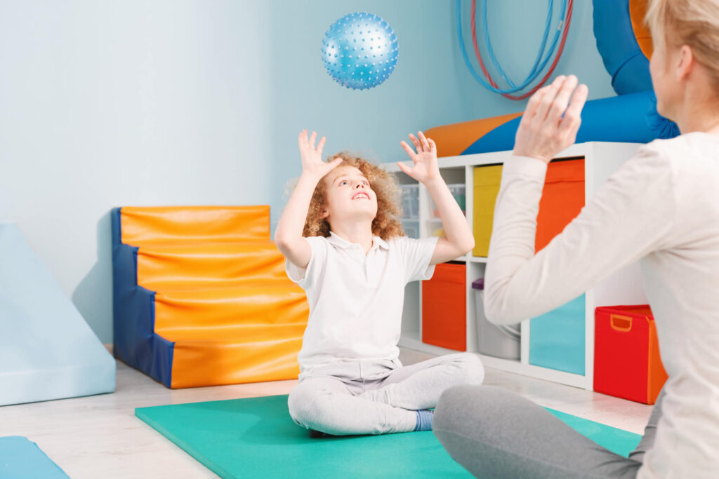 boy and therapist playing catch in a calming room