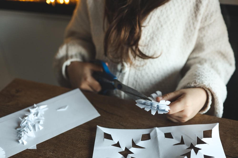 The Importance of Scissor Skills in Child Development: Tips and Activities to Get Started 8 girl making a paper snowflake from folded paper